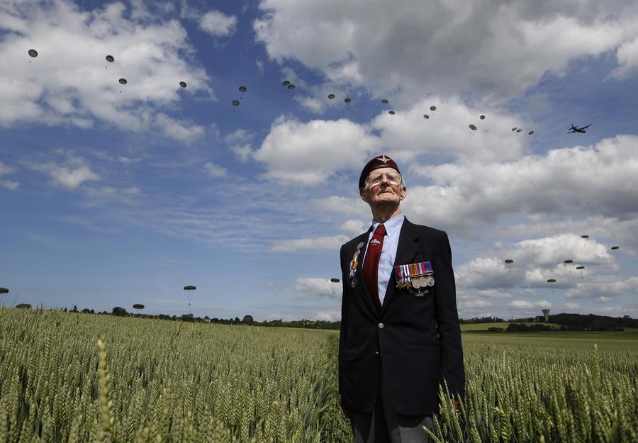 Le vétéran britannique originaire de Brighton, Fred Glover,88 ans, acteur du débarquement en Normandie, prend la pose devant un écran d’une patrouille de 300 parachutistes internationaux à Ranville (France), le 5 juin 2014. Glover, du 9e bataillon de parachutistes, a pris part le Jour J à à une attaque de planeurs contre une batterie d'artillerie allemande à Merville. Près de 3000 anciens combattants ont assisté à plusieurs cérémonies sur les c?tes normandes où les forces alliées ont débarqué dans la plus grande invasion maritime de l'histoire, il y a soixante-dix ans pour aider à accélérer la défaite de l'Allemagne nazie pendant la Seconde Guerre mondiale. [Photo/agences]