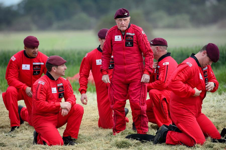 Le vétéran de la Seconde Guerre mondiale, l’Anglais Jock Hutton (centre), 89 ans, après son atterrissage avec des parachutistes fran?ais, américains, canadiens et britanniques lors d'une commémoration du jour J à Ranville, dans le nord de la France, le 5 juin 2014. [Photo/agences]