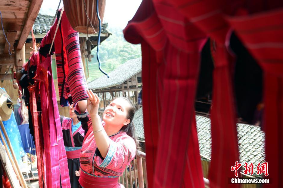 Une jeune de l'ethnie Yao aère sa veste rouge et sa belle robe préservées préserve dans une bo?te