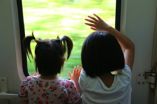 Les deux s?urs regardent à travers une fenêtre de leur train en direction de Shunde, où leurs parents travaillent, le 10 juillet 2014.