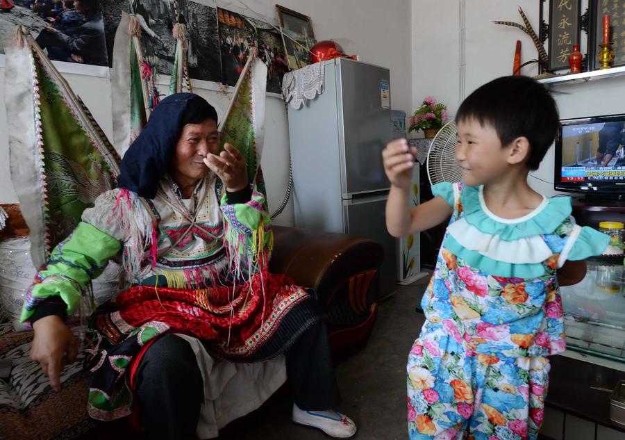 Photo prise le 24 juillet montrant Zhan Xueyan, à gauche, un héritier de l’Opéra d’Anshun, enseigner le jeu traditionnel à son petit-fils, à Anshun, dans la Province du Guizhou. [Photo / Xinhua]