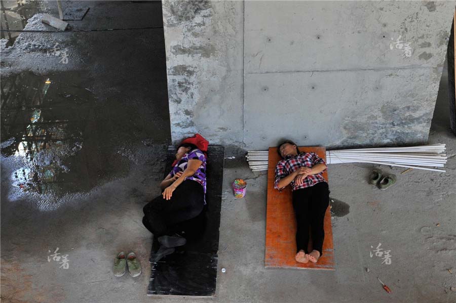 Deux femmes dorment sur des planches de bois lors de la pause déjeuner sur un chantier de construction. [Photo/qq.com]