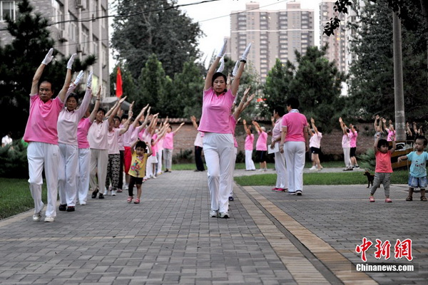 Sur un espace libre d’une résidence de la rue Guangqu, les habitants se rassemblent en un groupe bien aligné pour pratiquer la ? danse des zombies ?. Nombre de ces amis de la danse s’habillent de manière uniforme, et à c?té d’eux quelques  enfants ont également rejoint l'équipe pour se joindre à la fête. Photo Jin Shuo pour Xinhua.