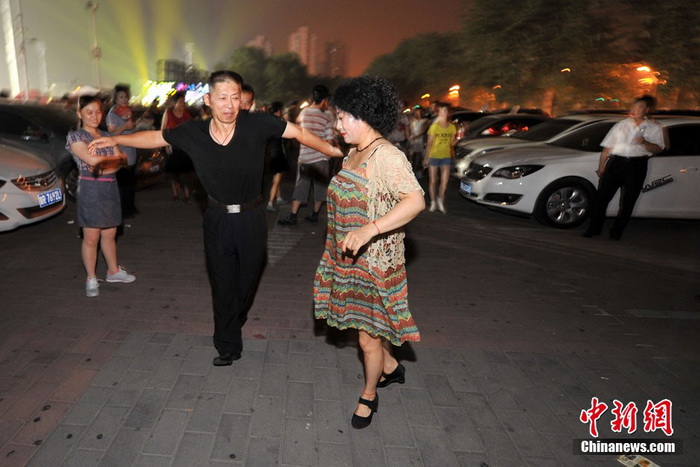 Sur le parking du gymnase de Wukesong, avenue Chang'an Ouest, un couple danse au son d'une musique puissante. Photo Jin Shuo pour Xinhua. 