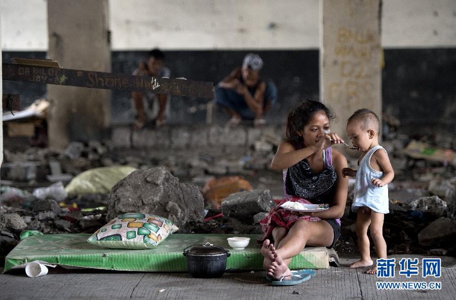 Le 28 ao?t 2014, à Manille, une jeune femme donne à manger à un enfant sous un pont routier, l’endroit où elle vit. 