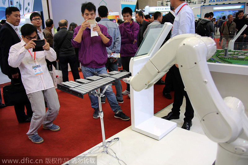 Deux hommes photographient un bras robotisé jouant du xylophone de plage pendant le 16e Salon international de l'industrie de Chine à Shanghai, le 4 novembre 2014. 