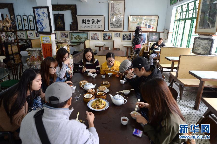 Des jeunes de Aomen (澳門) prennent le petit-déjeuner dans la maison de thé de Longhua. Etant l’établissement le plus ancien de la ville, Longhua a su préserver une authentique gastronomie locale.