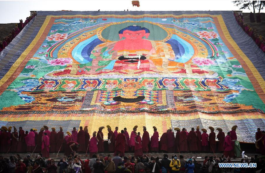 Plusieurs lamas et bouddhistes participent au rituel annuel de l'exposition d'une gigantesque thangka (peinture religieuse tibétaine) proche d'une colline pour le culte de disciples au monastère de Labrang à Xiahe, dans la province chinoise du Gansu (nord-ouest de la Chine), le 3 mars 2015. L'événement de la thangka, ou "l'exposition au soleil du Bouddha", lors des traditionnelles prières bouddhistes pour une bonne année. [Photo/Xinhua]