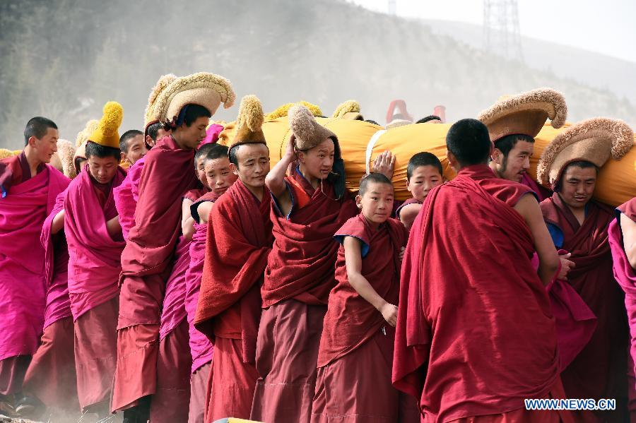 Des lamas portent sur l'épaule une immense thangka (peinture religieuse tibétaine) vers une colline pour le rituel annuel au monastère de Labrang à Xiahe, dans la province chinoise du Gansu (nord-ouest), le 3 mars 2015. [Photo/Xinhua]