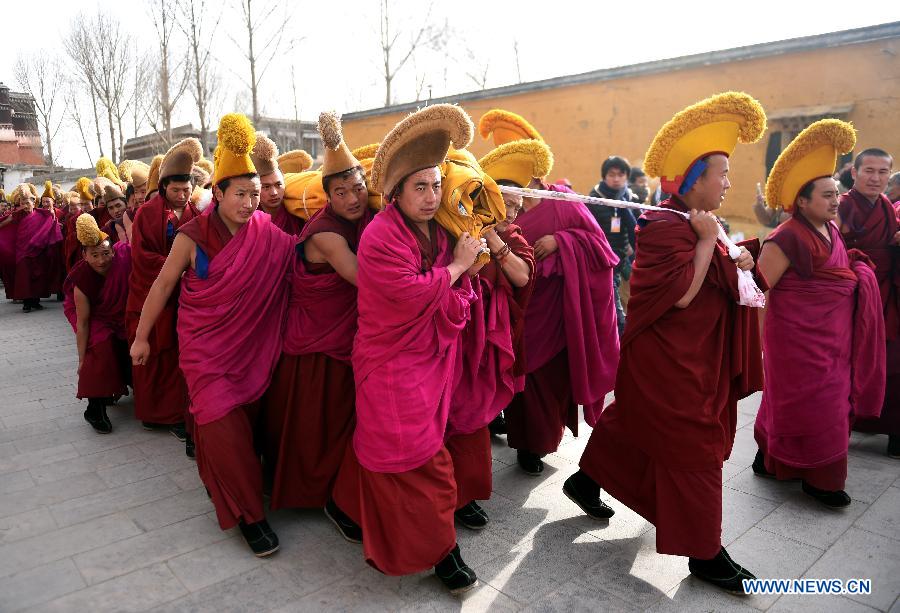 Des lamas portent sur l'épaule une immense thangka (peinture religieuse tibétaine) vers une colline pour le rituel annuel au monastère de Labrang à Xiahe, dans la province chinoise du Gansu (nord-ouest), le 3 mars 2015. [Photo/Xinhua]