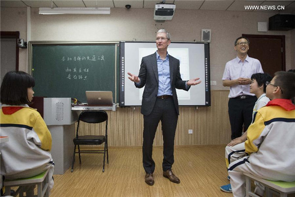 Tim Cook, au centre, échange avec des élèves lors d’une le?on à l'école primaire de l'Université de Communication de Chine, le 12 mai 2015. [Photo / Xinhua]