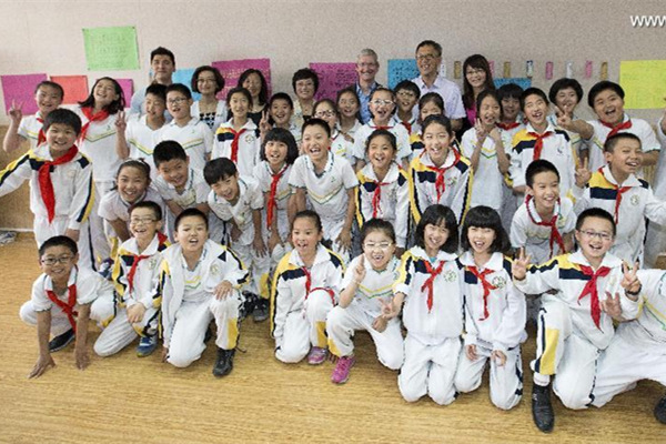 Tim Cook, au fond, pose pour une photo de groupe avec les enseignants et les élèves de l'école. [Photo / Xinhua]