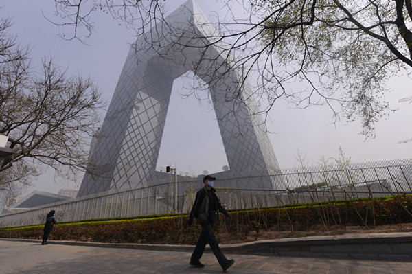 Un passant portant un masque, près du batiment de CCTV à Beijing, lors d'une journée brumeuse en avril dernier. [Photo/Wei Xiaochen/Asianewsphoto] 