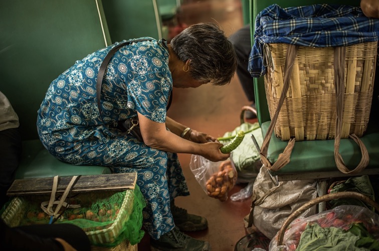 Avant de démarrer les ventes, une femme agée profite d’une pause dans le train pour prendre son petit déjeuner, au menu un concombre et du pain cuit.