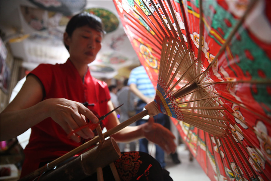 Une femme fabrique un parapluie de papier huilé dans le bourg de Fenshui, ville de Luzhou (province du Sichuan, Chine du Sud-Ouest), le 6 ao?t 2015.