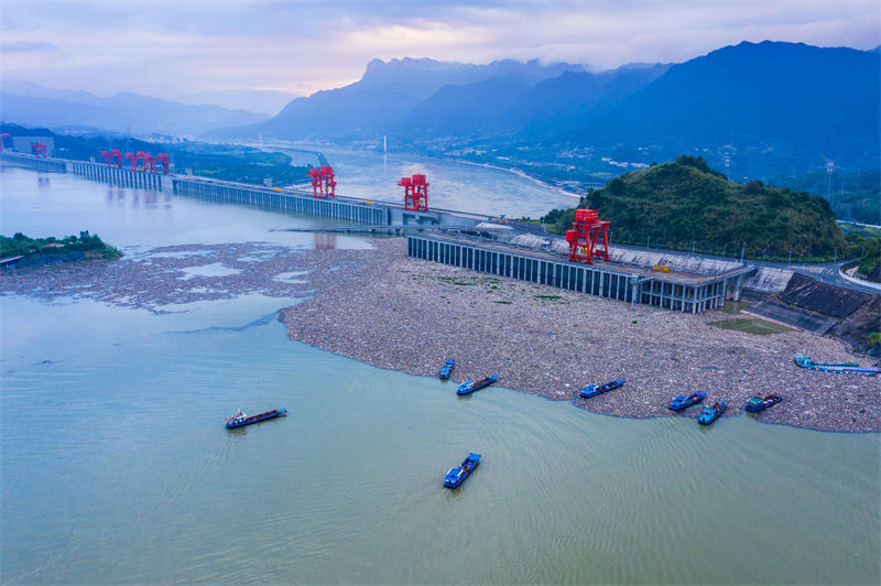 Des bateaux nettoient les objets flottants devant le barrage des Trois Gorges à Yichang, dans le Hubei