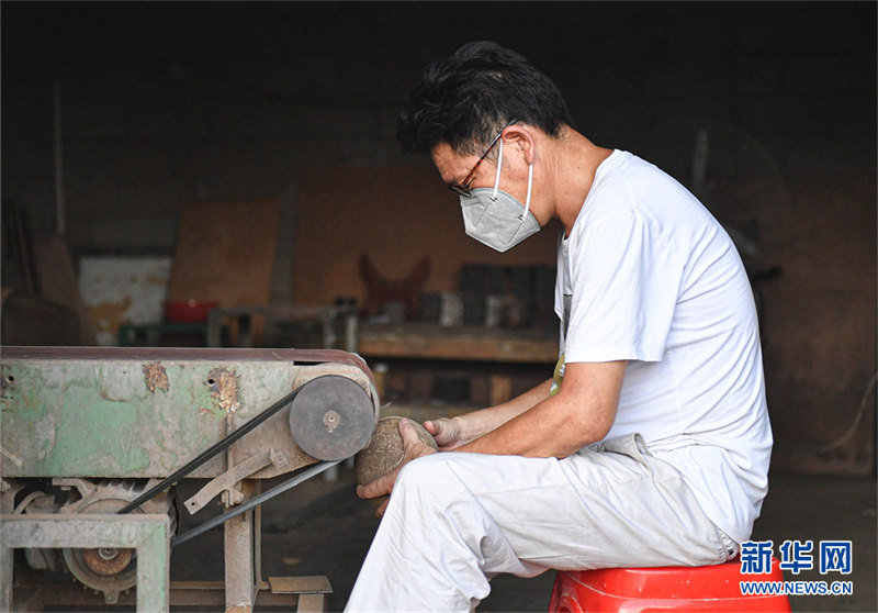 Un artisan gardant la sculpture de noix de coco millénaire