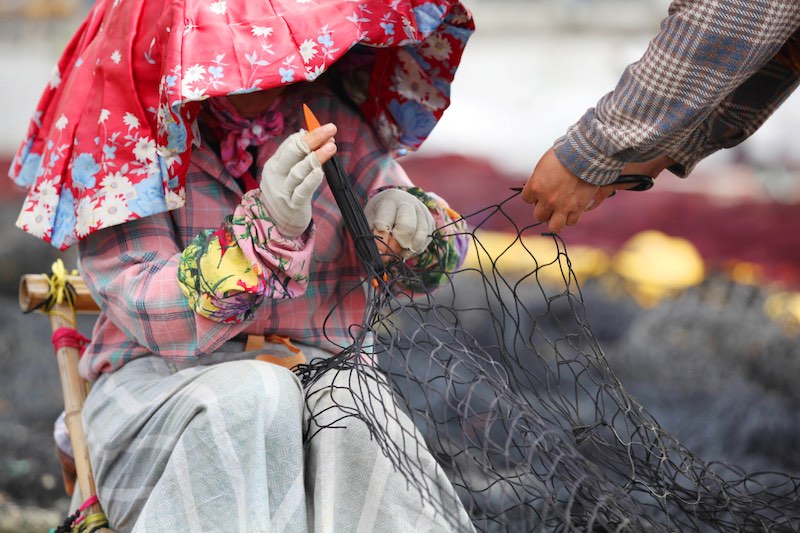 Pas de pêche, encore du travail : être occupés à repriser les filets de pêche