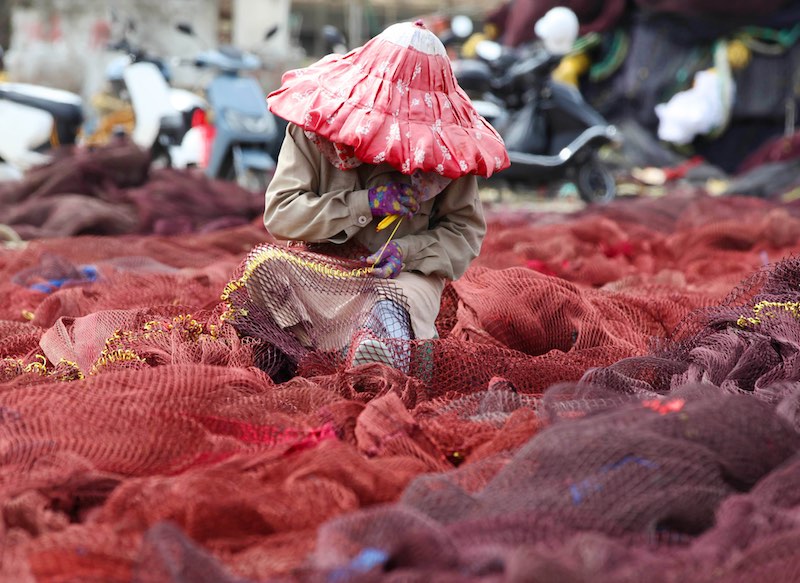 Pas de pêche, encore du travail : être occupés à repriser les filets de pêche