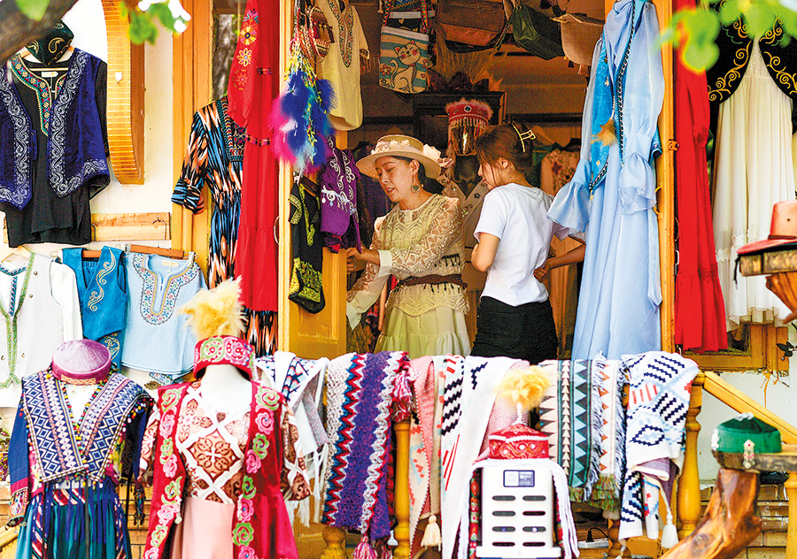 Des touristes choisissent des costumes folkloriques rue Liuxing, à Yining, dans la région autonome ou?ghoure du Xinjiang (nord-ouest de la Chine), le 17 mai. (Photo / Xinhua)