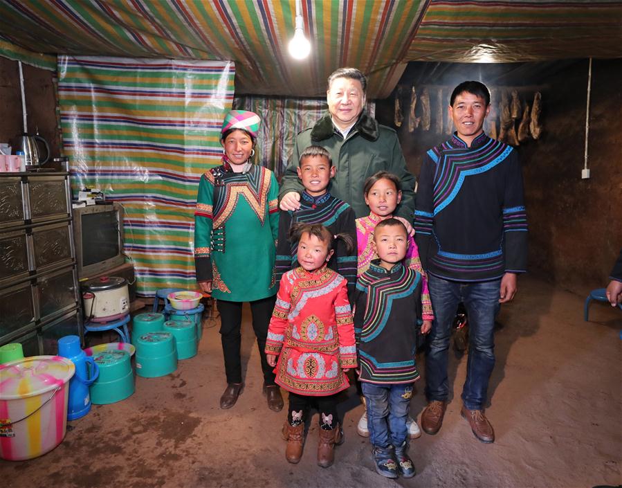 Le président Xi Jinping pose pour une photo de groupe avec une famille démunie du village de Sanhe de la préfecture autonome yi de Liangshan. (Photo/Xinhua)