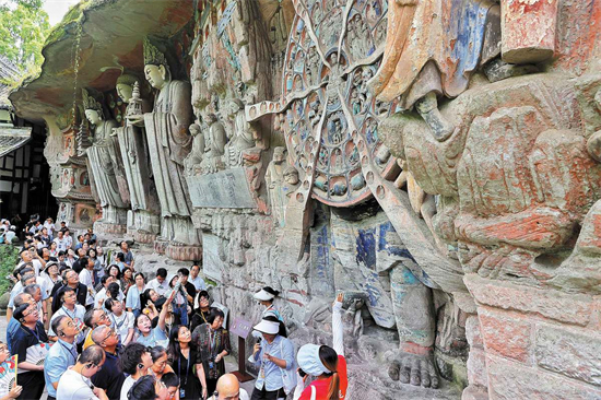 Les visiteurs apprécient les gravures rupestres du mont Baoding. (Jiang Dong / China Daily)