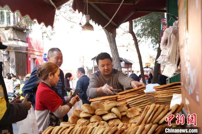 Abdusattar Ubul (à droite) choisit du nang pour ses clients. (Gou Jipeng / China News Service)