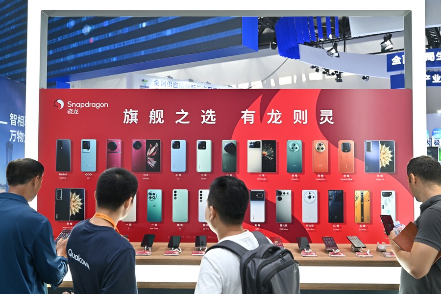 Des visiteurs regardent des téléphones portables dotés de puces Qualcomm Snapdragon sur le stand de Qualcomm lors de la Foire internationale du commerce des services de Chine (CIFTIS) 2023, au Centre national des conventions de Chine, à Beijing, capitale chinoise, le 4 septembre 2023. (Photo : Li Xin)