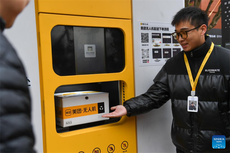 Un membre du personnel montre la réception d'un colis alimentaire livré par un drone à l'école supérieure internationale de Tsinghua à Shenzhen, dans la province du Guangdong (sud de la Chine), le 19 décembre 2023. (Xinhua/Mao Siqian)