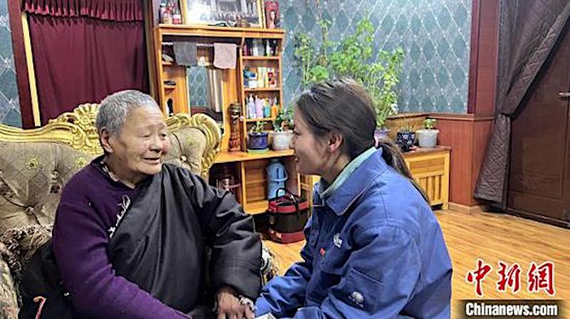 Zaxi Lamao (à droite) explique à une personne agée les précautions à prendre concernant l