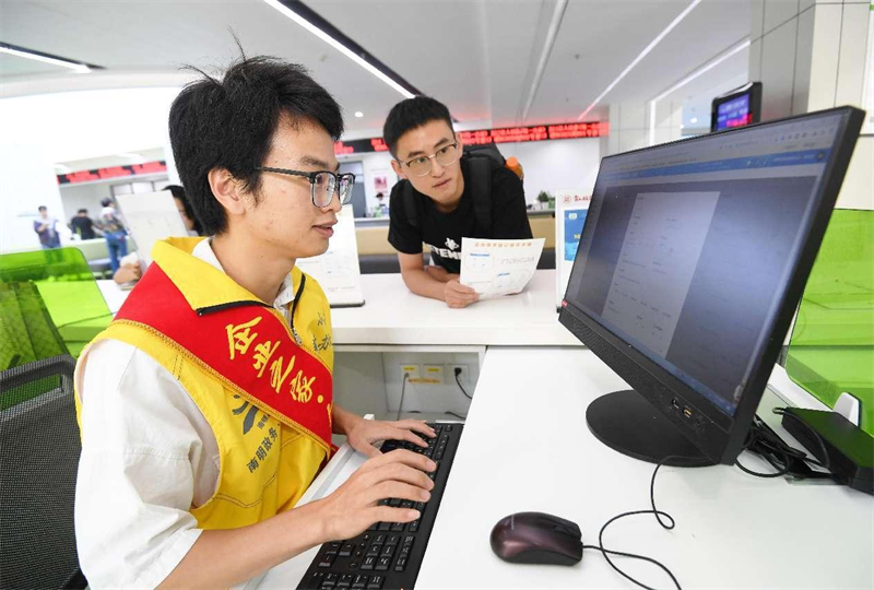 Un membre du personnel d'un centre de services gouvernementaux du district de Nanming, à Guiyang, capitale de la province du Guizhou (sud-ouest de la Chine), enregistre les demandes d'une entreprise. (Zhao Song / Pic.people.com.cn)