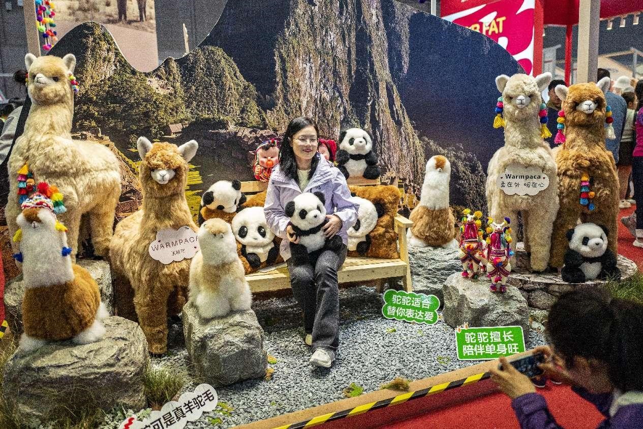 Une visiteuse pose pour une photo au stand d'exposition de la marque péruvienne Warmpaca à la 7e Exposition internationale d'importation de Chine (China International Import Expo, CIIE), le 9 novembre 2024. (Wang Chu / Le Quotidien du Peuple en ligne)