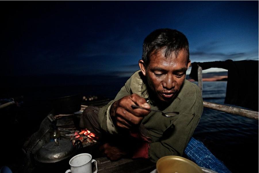 Un homme prend son d?ner à bord de son bateau.