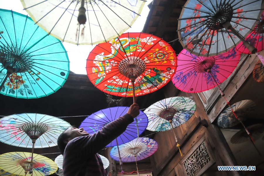 Un artisan regarde des parapluies de papier huilé dans un atelier du district de Xixiu, à Anshun, ville de la province du Guizhou (sud-ouest), le 12 novembre 2012. Fabriqué en papier huilé et doté d'une armature en bambou, ce type de parapluie est un objet artisanal traditionnel chinois. Les techniques de fabrication du parapluie de papier huilé ont été introduites au Guizhou durant la dynastie Ming. (Photo : Huang Yong)