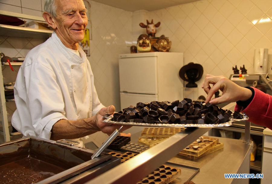 Un employé (à gauche) invite un visiteur à go?ter des chocolats au Musée du cacao et du chocolat de Bruxelles, à l'occasion de la semaine du chocolat organisée dans la capitale belge, le 21 novembre 2012. (Photo : Yan Ting)