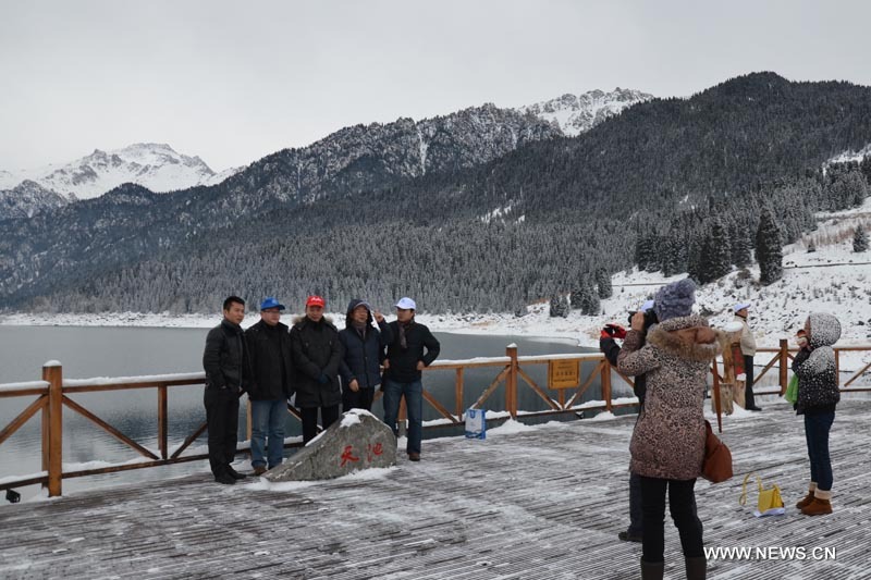 Des touristes posent pour des photos sur le site touristique de Tianchi dans les monts Tianshan, dans la région autonome ou?goure du Xinjiang (nord-ouest), le 1er décembre 2012. Le Festival de glace et de neige de Tianchi a ouvert samedi sur ce site touristique. (Photo : Yu Tao)