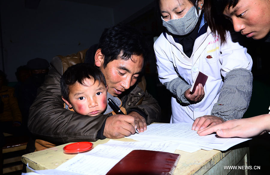 Chagba (deuxième à gauche), père de Luozhou Jigme, un gar?on souffrant d'une maladie cardiaque congénitale, signe le formulaire de consentement pour une opération, dans le district de Nangqian de la province du Qinghai (nord-ouest), le 3 décembre 2012.