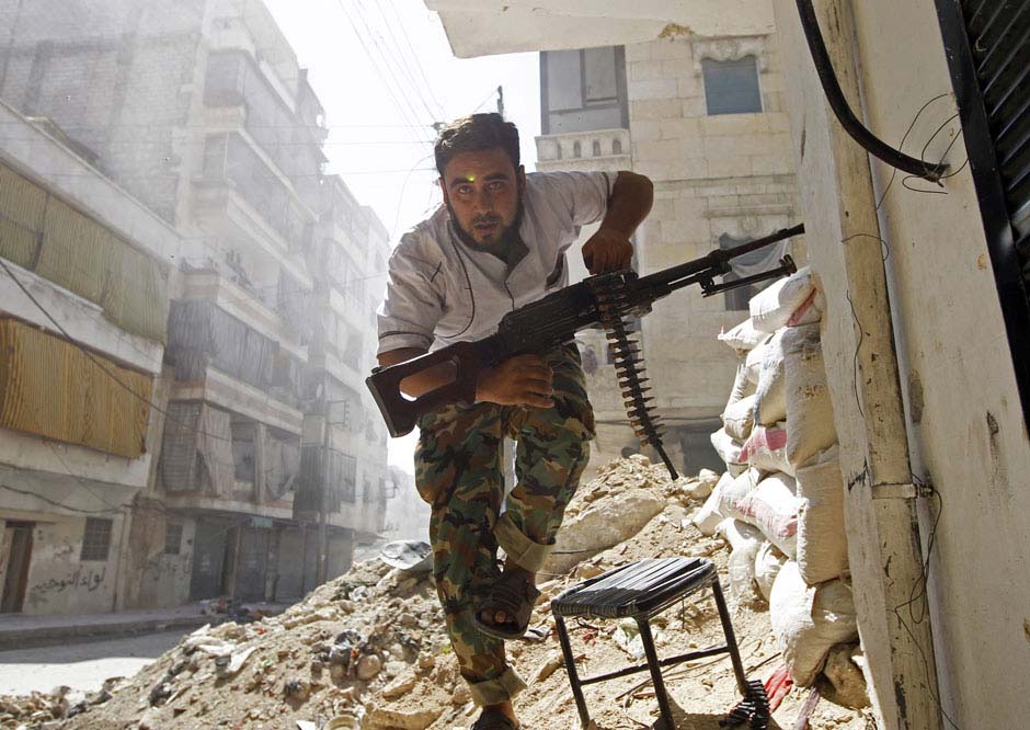 Le 7 ao?t 2012 dans une rue de la ville d'Alep en Syrie, un combattant de l'Armée libre syrienne cherche un abri pendant un accrochage avec l'Armée gouvernementale du pays. REUTERS / Goran Tomasevic