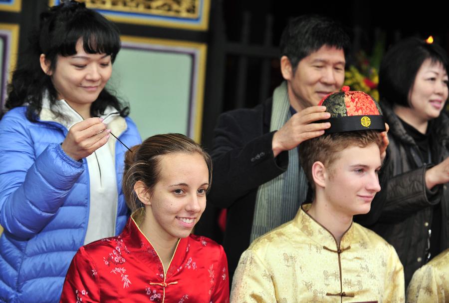 Deux étudiants, en plein rituel, l'épingle dans les cheveux pour la jeune fille et la coiffe du traditionnel chapeau chinois pour le gar?on, lors de leur cérémonie du passage à la majorité qui a été organisée, dimanche 9 décembre 2012, dans le Temple de Confucius à Taipei, capitale de la province de Ta?wan en Chine. (Xinhua/Wu Ching-teng)