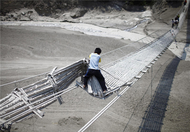 Un jeune gar?on tente de traverser un pont suspendu endommagé, après une crue soudaine causée par une avalanche dans le District de Kaski, dans le Massif de l'Annapurna, le 6 mai 2012.