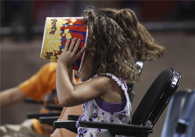 Une jeune fan de baseball s'assure qu'il ne lui reste plus un grain de pop-corn alors qu'elle regarde les Cubs de Chicago jouer contre les Diamondbacks de l'Arizona lors de leur match de baseball de la Ligue nationale MLB à Phoenix, dans l’Arizona, le 24 juin 2012.