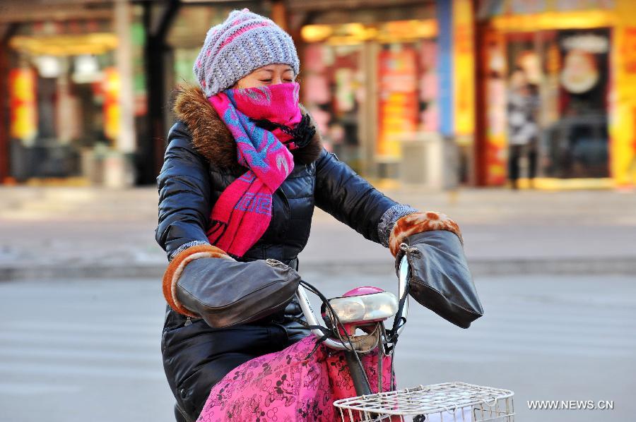 Une habitante locale roule dans le vent froid à Baoding, dans la province du Hebei (nord), le 23 décembre 2012. Le centre météorologique de la province a émis une alerte bleue au froid samedi. La plupart du Hebei a souffert d'une chute brutale des températures et de grands vents.