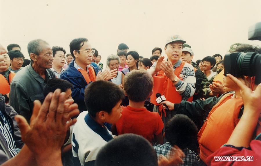 Photo d'archive prise le 20 ao?t 1998 montrant Zhang Dejiang (à droite) rendant visite aux victimes des inondations afin de diriger les opération de secours dans le bourg de Gashigen dans le district de Zhenlai de la province du Jilin (nord-est), en Chine.