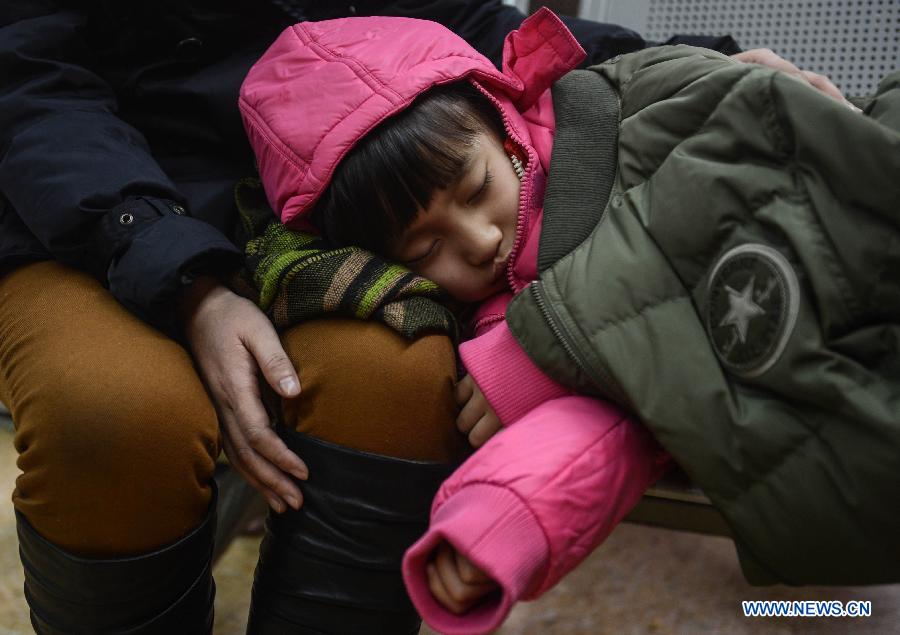 Le 27 janvier 2013 à la gare de Hangzhou, en attendant son train pour Qiqihaer, une ville de la province chinoise du Heilongjiang, une petite fille s'endort sur les genoux de sa mère. (Xinhua/Han Chuanhao)