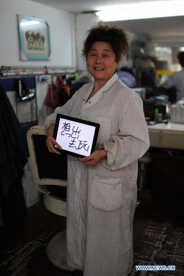 Mme Wu, coiffeuse agée de 55 ans, souhaite un jour de congé pour la Journée de la femme, à Nanchang, capitale de la province orientale du Jiangxi, en Chine, le 7 mars 2013.