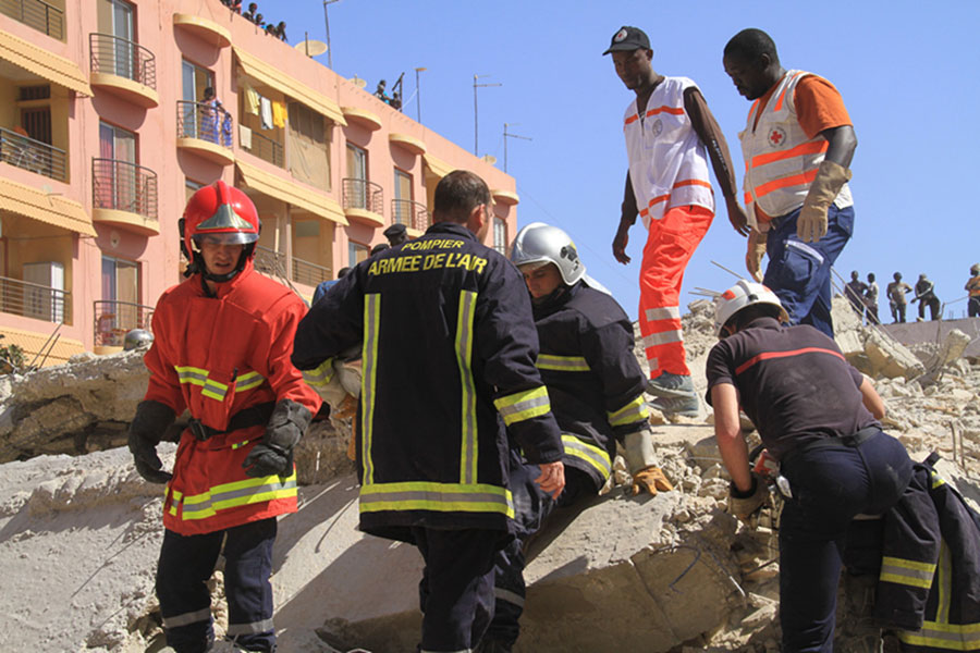 Les troupes fran?aises au Sénégal et les secouristes et travailleurs médicaux locaux participent aux opérations de secours sur le site de l'effondrement d'un batiment à Dakar, capitale du Sénégal, le 8 mars 2013. Environ dix ouvriers ont été ensevelis dans les décombres d'un batiment et une enquête a été ouverte pour déterminer le nombre exact de victimes. (Photo : Tai Jianqiu)