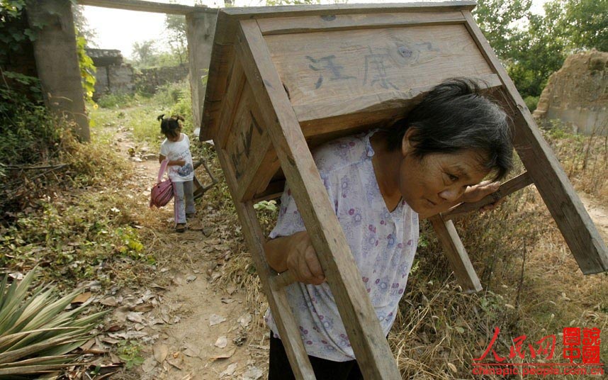 A Macheng, dans la Province du Hubei, une petite fille transporte sa chaise sur le chemin de l'école, tandis que sa grand-mère l'aide en portant son pupitre. A l'école primaire locale, de nombreux étudiants apportent leurs propres tables et chaises à l'école.