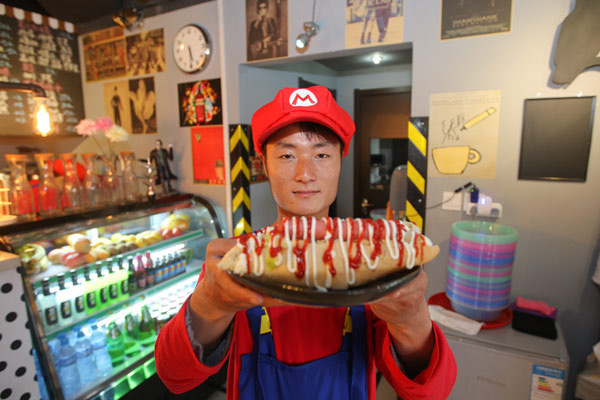 Un jeune homme portant la tenue du héros ? Super Mario ? fait le service dans un restaurant à Tianjiin. L'établissement qui a repris le thème du célèbre jeu vidéo Super Mario, est ouvert au public depuis le 8 avril 2013. [Photo/Asianewsphoto ]