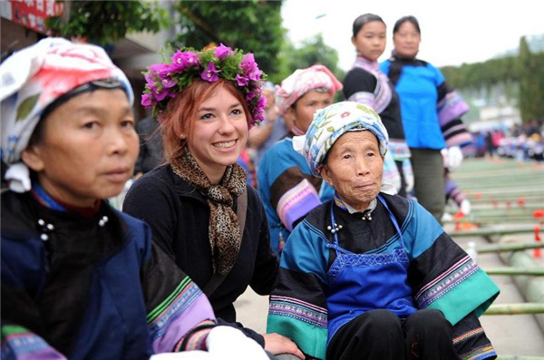 Une jeune fran?aise (au centre, devant) pose pour une photo de groupe avec des femmes de l'ethnie Dai lors du festival de la culture et des coutumes folkloriques marquant le ? San Yue San ? (le troisième jour du troisième mois lunaire du calendrier chinois) dans le Comté de Shizong, dans la Province du Yunnan, dans le Sud-ouest de la Chine, le 12 avril 2013. La Fête du San Yue San, qui attire des dizaines de milliers d’habitants locaux et les touristes venant à la fois de Chine et de l'étranger, a eu lieu ici vendredi. [Photo / Xinhua]