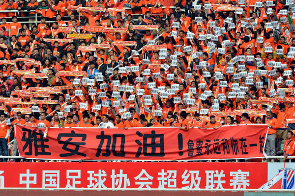 Les spectateurs brandissent des bannières où l’on peut lire ? Courage, Ya'an ! ?, pour les habitants de la zone sinistrée lors d'un match de football de la Super League chinoise dans la ville de Jinan, dans la Province du Shandong, dans l’Est de la Chine, le 20 avril 2013. [Photo / Xinhua]